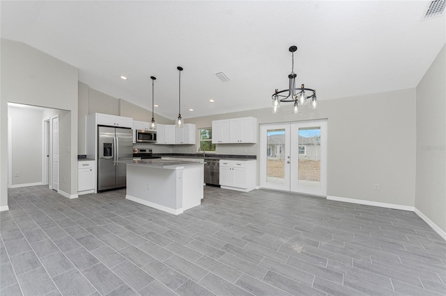 kitchen with stainless steel appliances, decorative light fixtures, a center island, and white cabinets