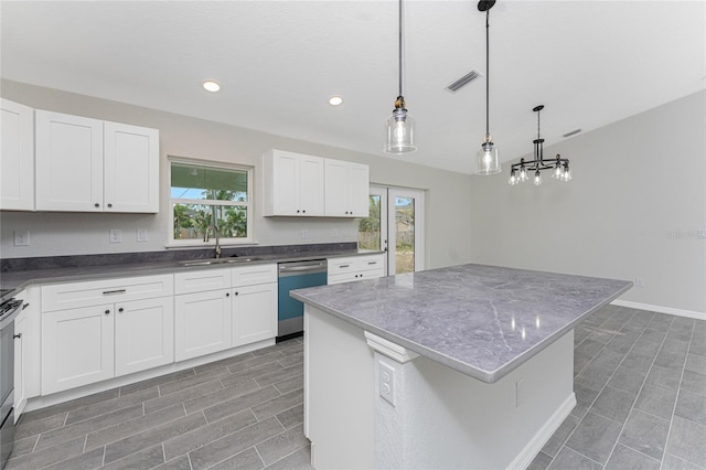 kitchen with hanging light fixtures, stainless steel appliances, a kitchen island, white cabinets, and sink