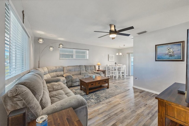 living room with hardwood / wood-style floors and ceiling fan with notable chandelier