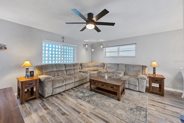 living room with a textured ceiling, light wood-type flooring, ceiling fan, and a healthy amount of sunlight