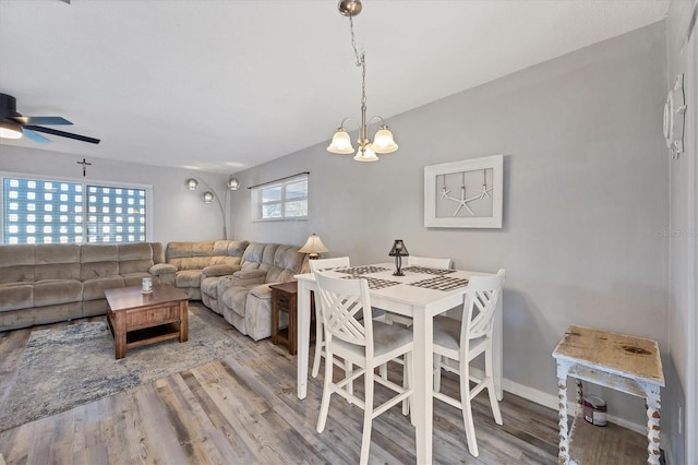 dining area with light wood-type flooring and ceiling fan with notable chandelier