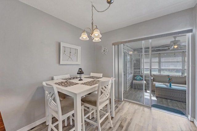 dining space with hardwood / wood-style floors and ceiling fan with notable chandelier