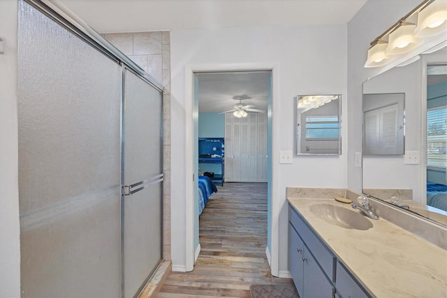 bathroom featuring hardwood / wood-style flooring, ceiling fan, a shower with door, and vanity