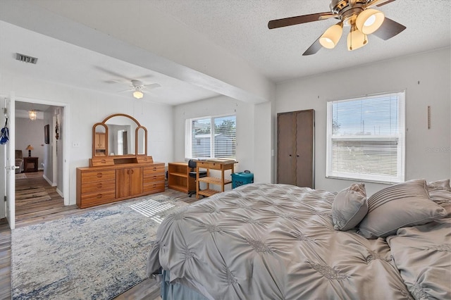 bedroom featuring hardwood / wood-style floors, ceiling fan, and a textured ceiling