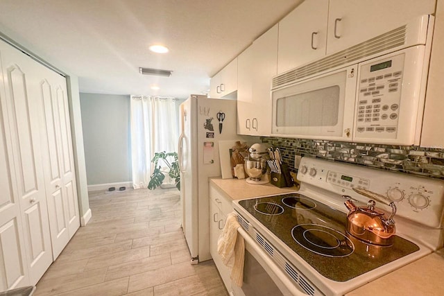 kitchen featuring white appliances, tasteful backsplash, and white cabinetry