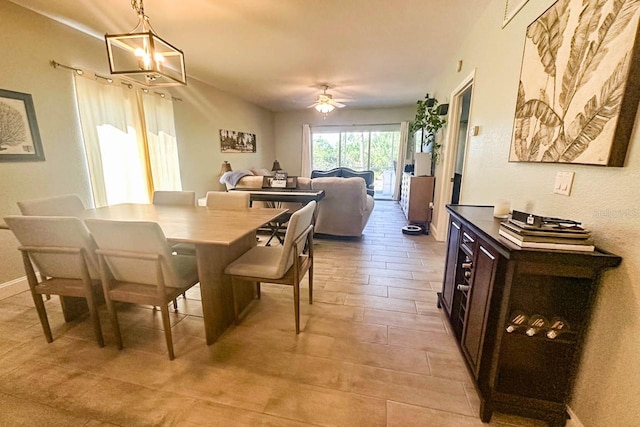 dining space with ceiling fan with notable chandelier