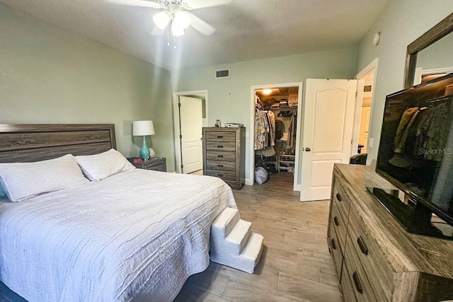 bedroom with a spacious closet, a closet, ceiling fan, and hardwood / wood-style flooring