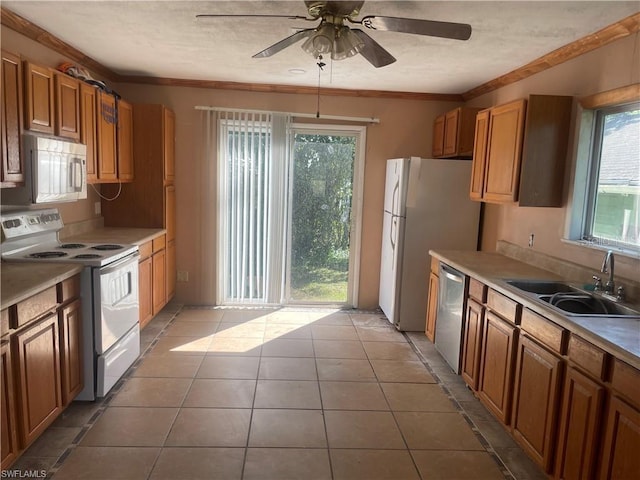 kitchen with sink, ceiling fan, light tile patterned floors, ornamental molding, and appliances with stainless steel finishes