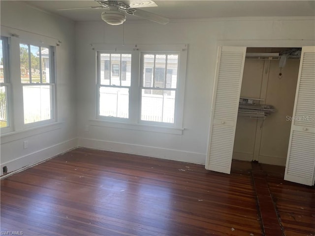 unfurnished bedroom with multiple windows, dark hardwood / wood-style flooring, and ceiling fan