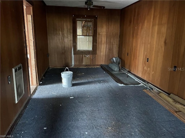 spare room featuring ceiling fan and wood walls