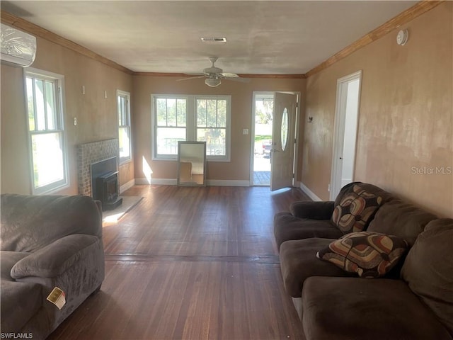 living room with a wood stove, ceiling fan, dark hardwood / wood-style floors, a wall unit AC, and crown molding