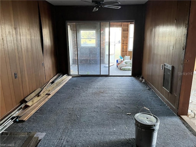 interior space featuring ceiling fan and wooden walls