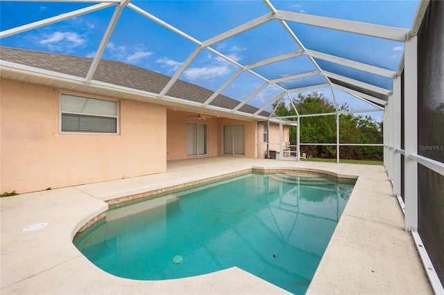 view of swimming pool featuring a patio, glass enclosure, and ceiling fan