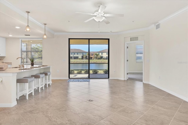 interior space featuring a water view, ceiling fan, crown molding, and sink