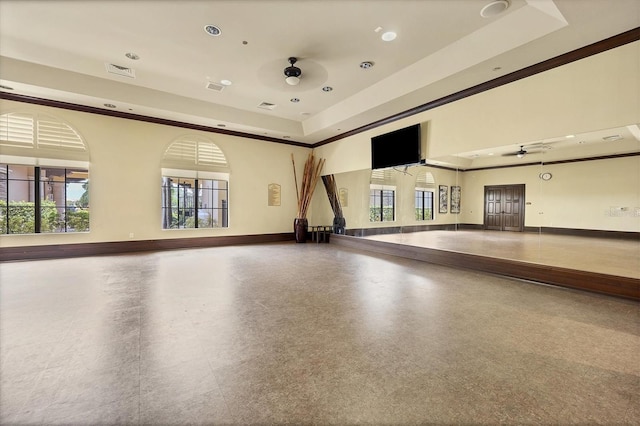 exercise room featuring a tray ceiling and ceiling fan