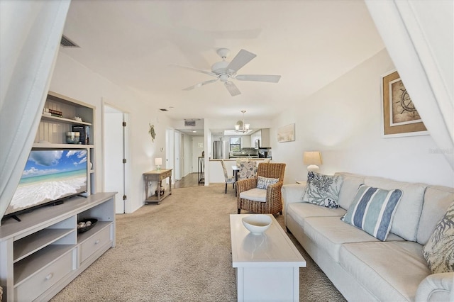 living room with ceiling fan with notable chandelier and light colored carpet