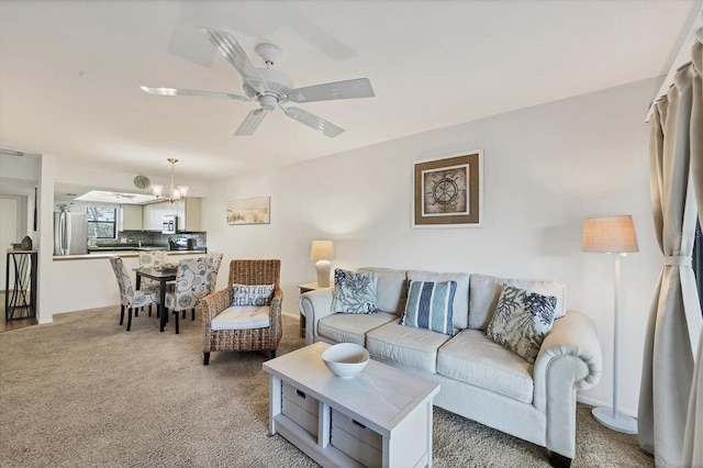 carpeted living room with ceiling fan with notable chandelier