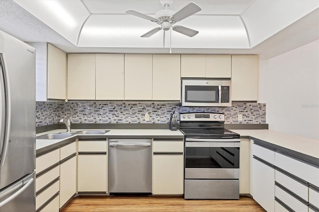 kitchen with cream cabinetry, sink, stainless steel appliances, and tasteful backsplash