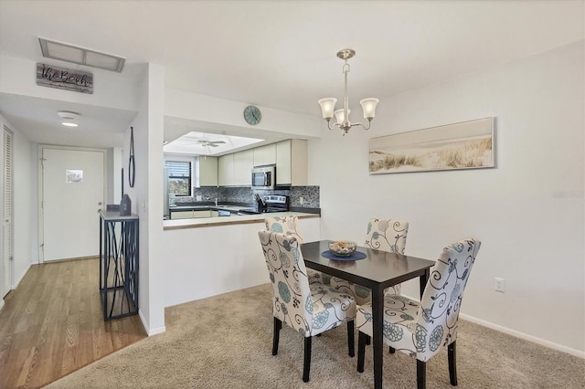 carpeted dining area featuring ceiling fan with notable chandelier