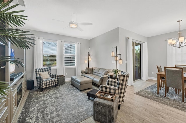 living room with ceiling fan with notable chandelier and light hardwood / wood-style flooring