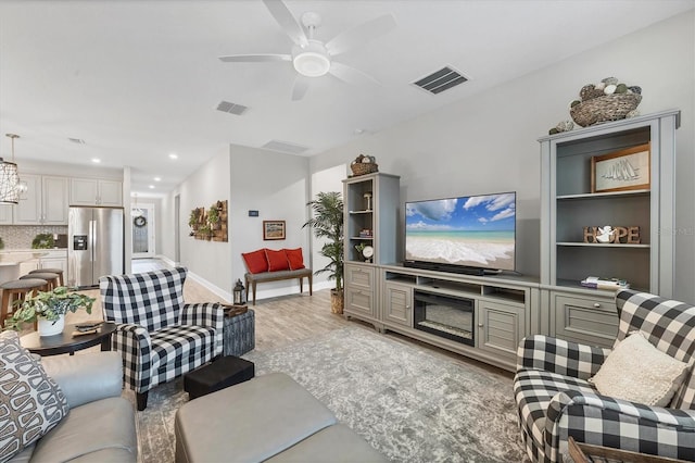 living room with ceiling fan and light hardwood / wood-style flooring