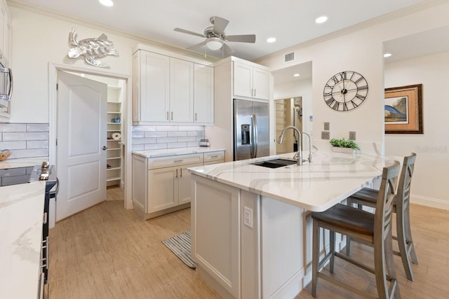 kitchen featuring stainless steel fridge, white cabinetry, sink, and tasteful backsplash