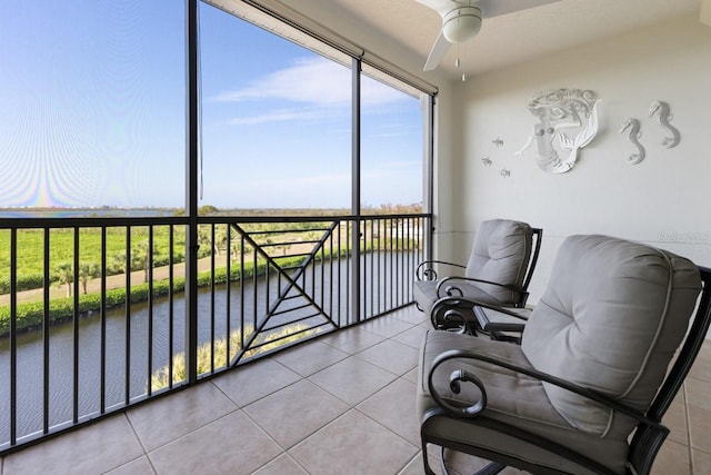 sunroom with ceiling fan and a water view