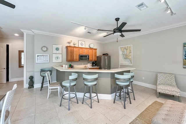 kitchen featuring a breakfast bar, ornamental molding, and appliances with stainless steel finishes