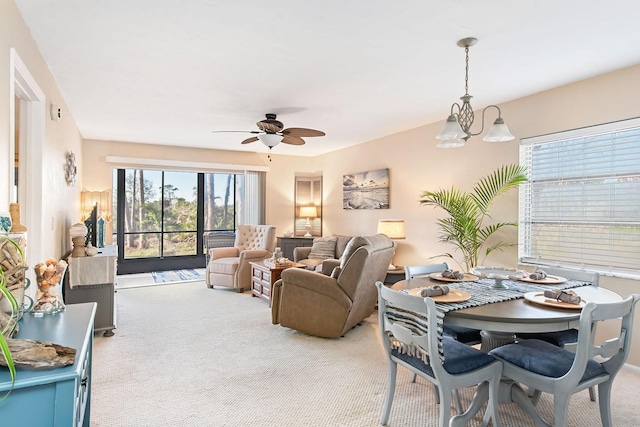 carpeted living room featuring ceiling fan with notable chandelier