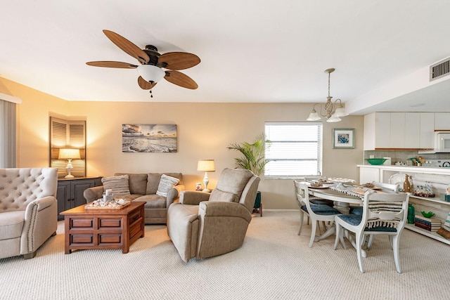 living room featuring light colored carpet and ceiling fan with notable chandelier