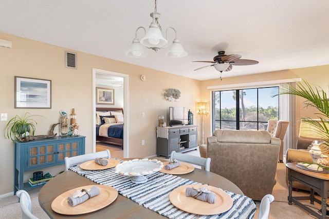 carpeted dining space with ceiling fan with notable chandelier