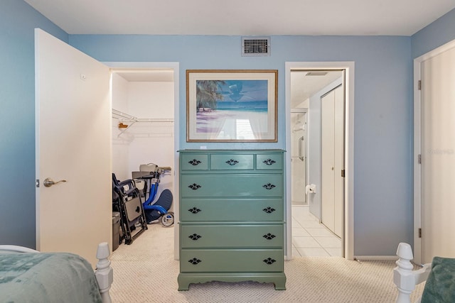 bedroom featuring a walk in closet, light carpet, and a closet