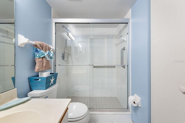 bathroom with a textured ceiling, vanity, toilet, and walk in shower