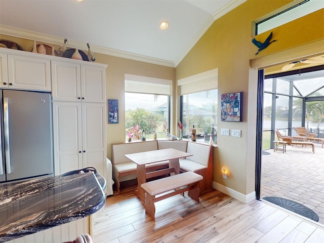 dining space with vaulted ceiling, ornamental molding, and light wood-type flooring