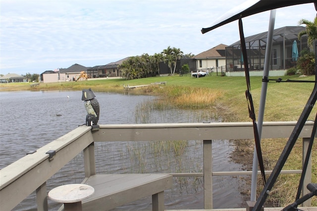 dock area with a lawn, glass enclosure, and a water view