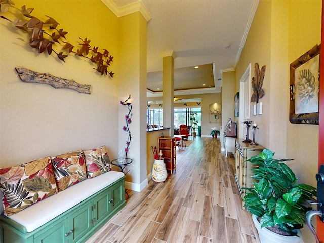 corridor with ornamental molding, light hardwood / wood-style floors, and a tray ceiling