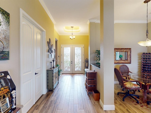 foyer with french doors, ornamental molding, an inviting chandelier, and light wood-type flooring