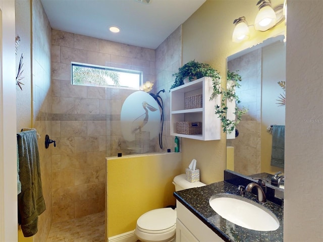 bathroom with tiled shower, vanity, and toilet