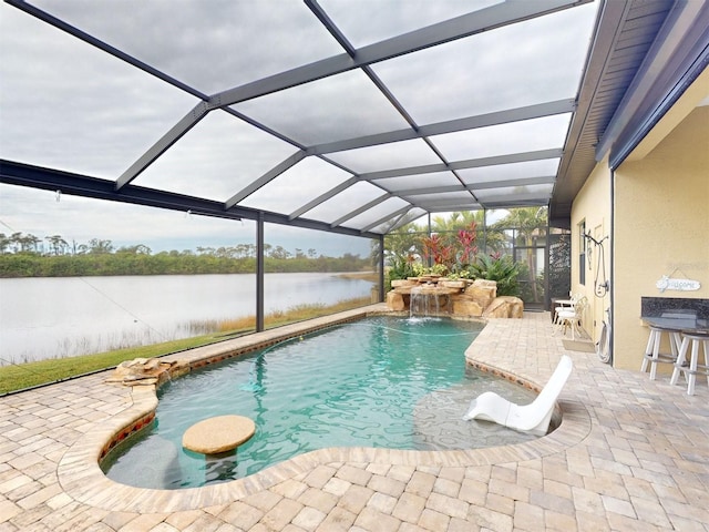 view of pool featuring pool water feature, a water view, a patio area, and glass enclosure