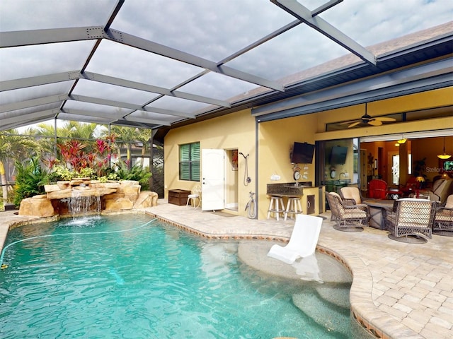 view of pool featuring exterior bar, pool water feature, a lanai, ceiling fan, and a patio area