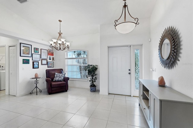 tiled foyer entrance with washer / dryer, a wealth of natural light, vaulted ceiling, and a notable chandelier