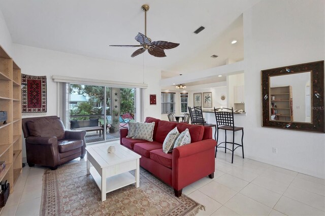 tiled living room with ceiling fan with notable chandelier