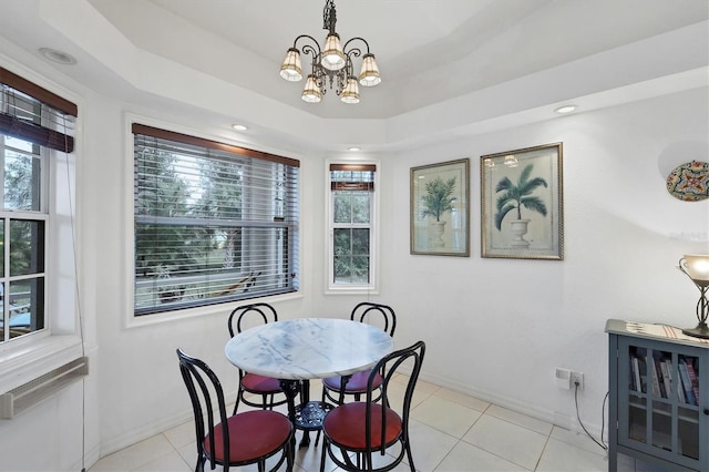 tiled dining room featuring a chandelier and a raised ceiling