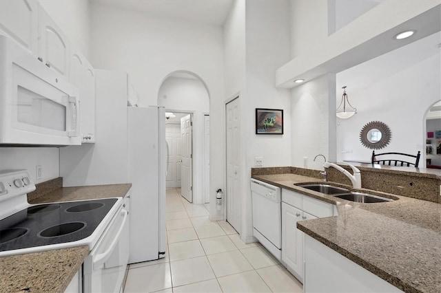 kitchen featuring sink, light tile patterned floors, a towering ceiling, white appliances, and white cabinets