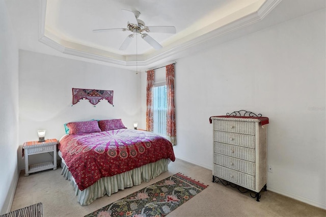 carpeted bedroom with ceiling fan, ornamental molding, and a tray ceiling