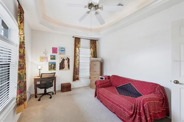 sitting room with ceiling fan, a raised ceiling, light colored carpet, and ornamental molding