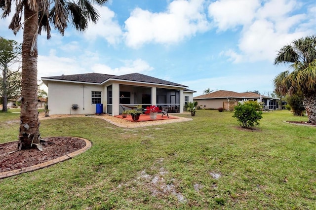 rear view of house featuring a lawn, a sunroom, and a patio area