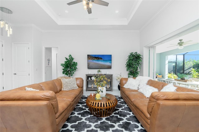 living room featuring ceiling fan, ornamental molding, and a tray ceiling