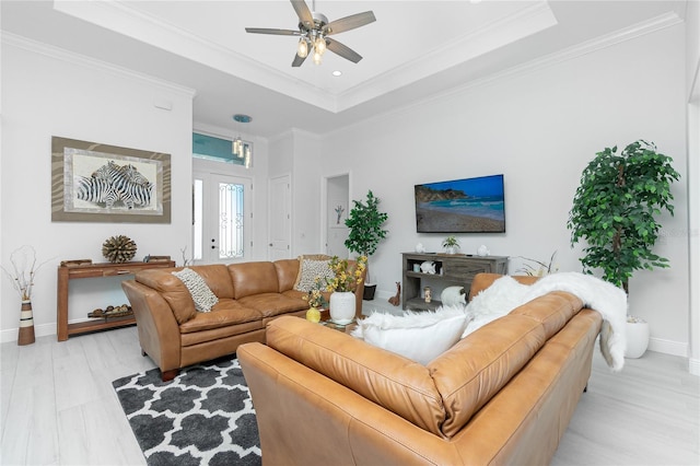 living room with a tray ceiling, ceiling fan, light hardwood / wood-style floors, and ornamental molding