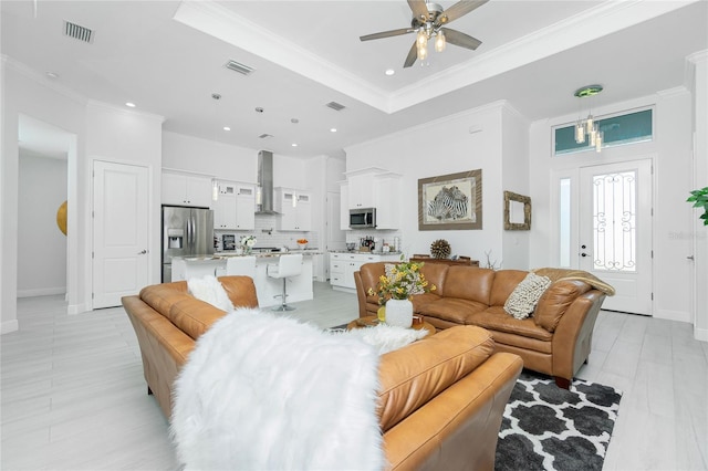 living room with a tray ceiling, ceiling fan, and crown molding